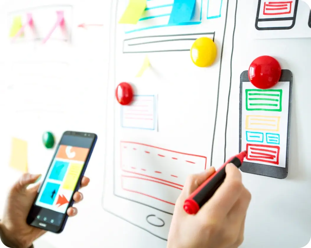 proof-of-concept-1 person holding phone and market creating wireframe on whiteboard.